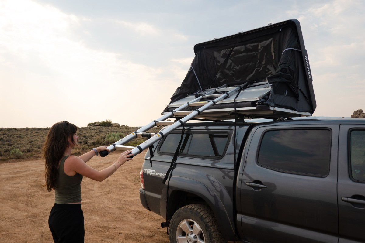 Woman using the ladder to fold the iKamper rooftop camper