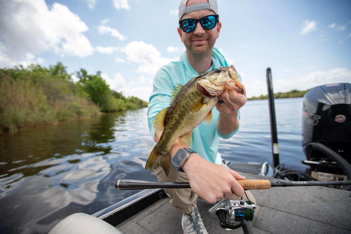 An angler holding a bass next to the H2oX Rod