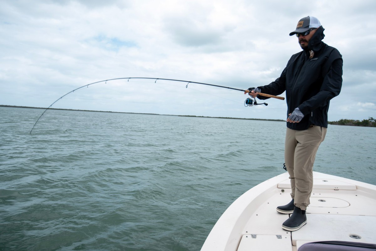 An angler fighting a fish on the bow of a boat in the ocean.