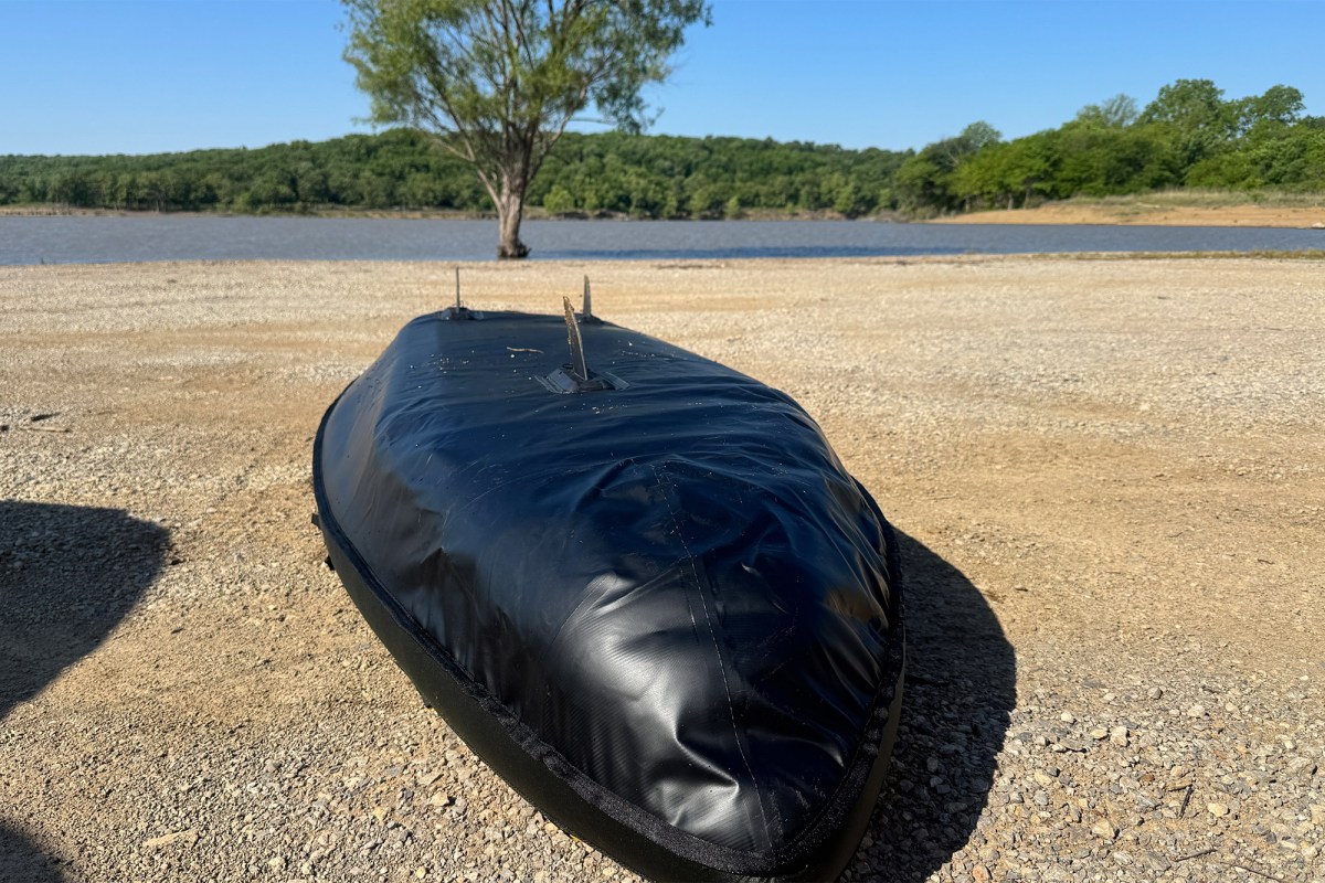 Bottom of the inflatable kayak resting on a gravel shore by the lake