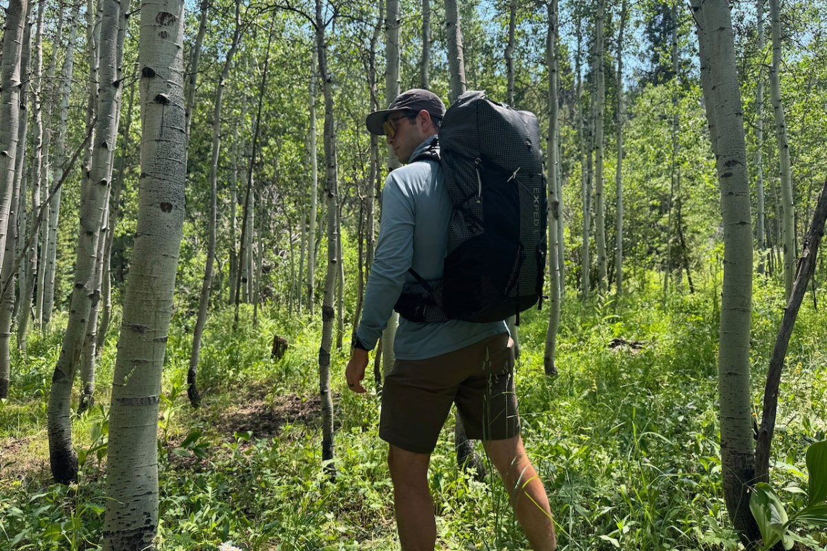 Hiker wearing the Exped backpack through an aspen forest