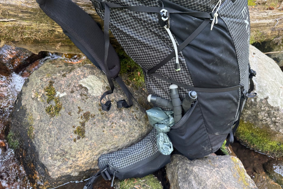Trekking pole handles stored in the side pocket of the hiking backpack
