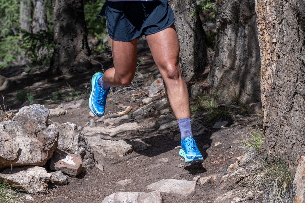 Close up of a woman running on a dirt singletrack trail 