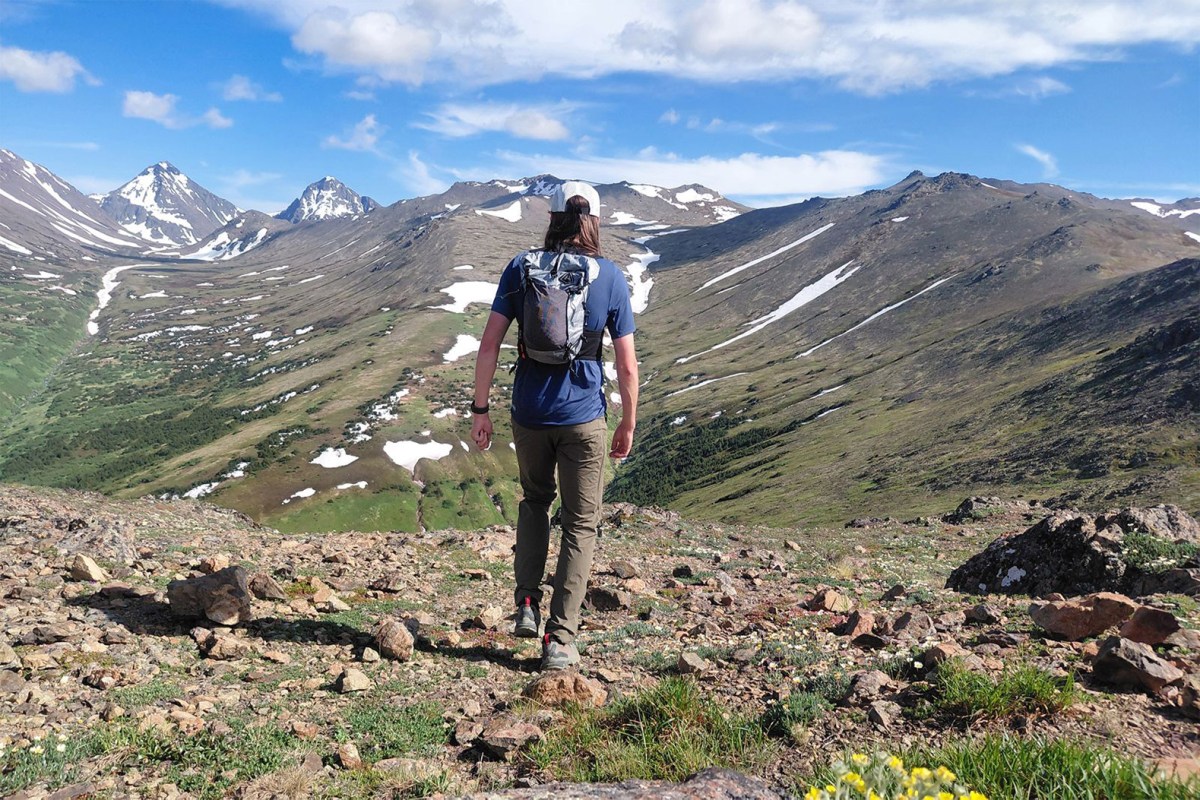 Hiker wearing the Pemi 15 while walking through a rocky alpine landscape