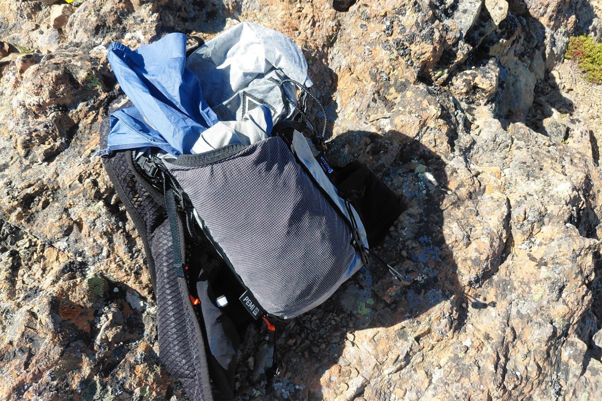 Pemi 15 pack open on rocky ground with layers stuffed inside