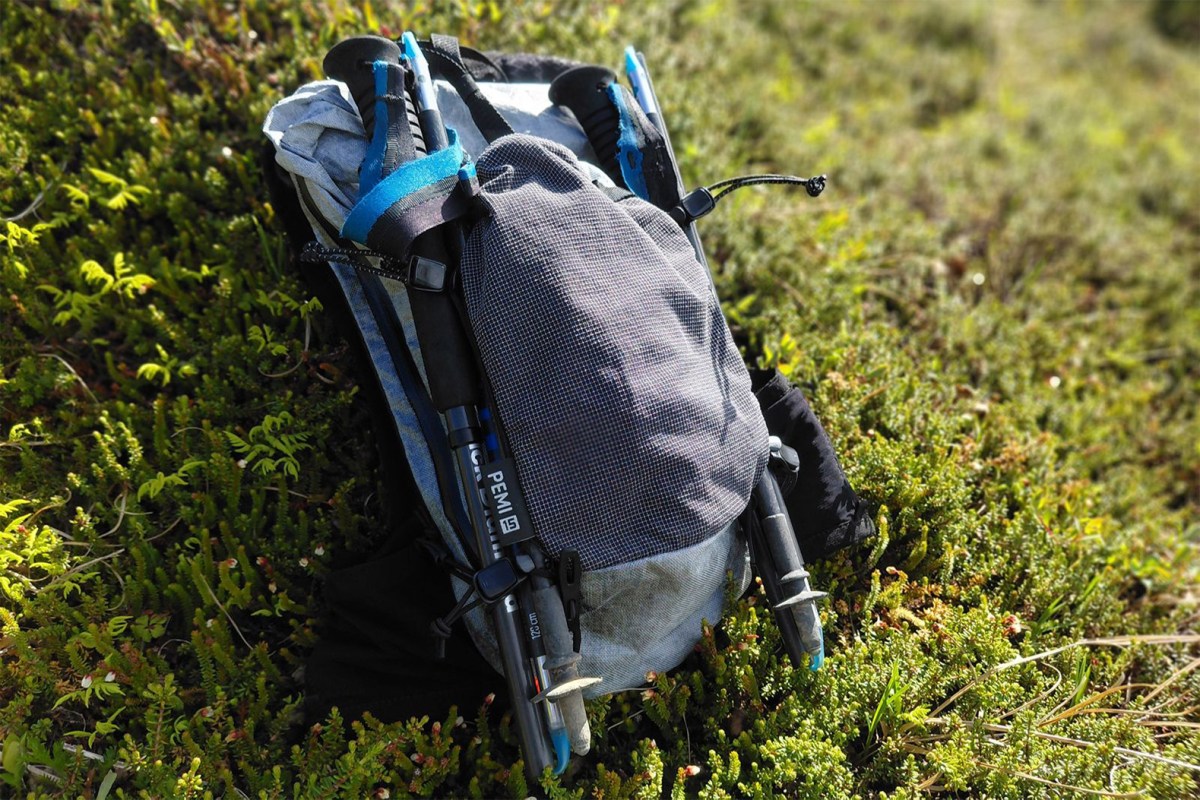 Hyperlite Pemi 15 packed with trekking poles attached on a grassy trail