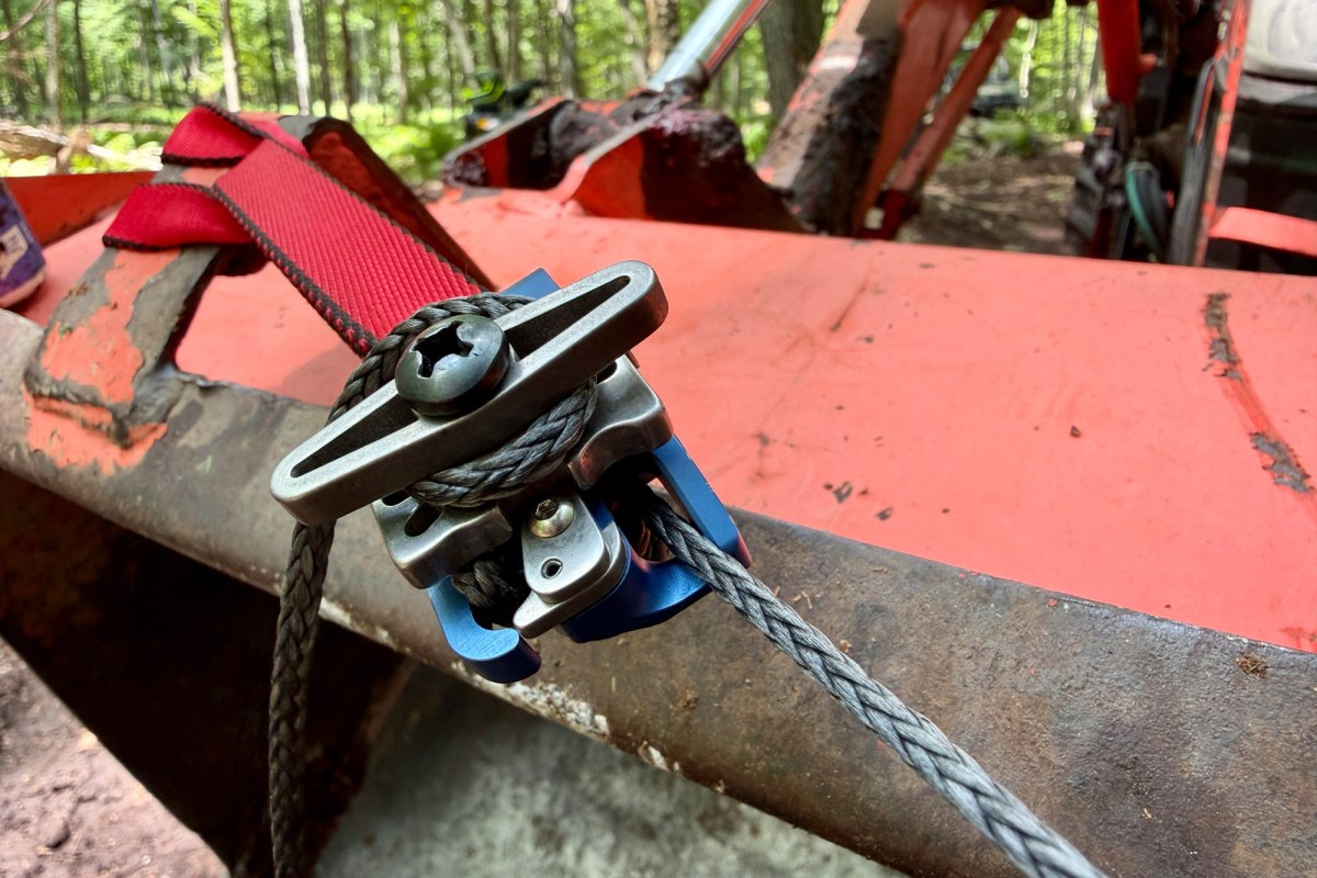 Close-up of the winch line secured to a tractor bucket while pulling logs