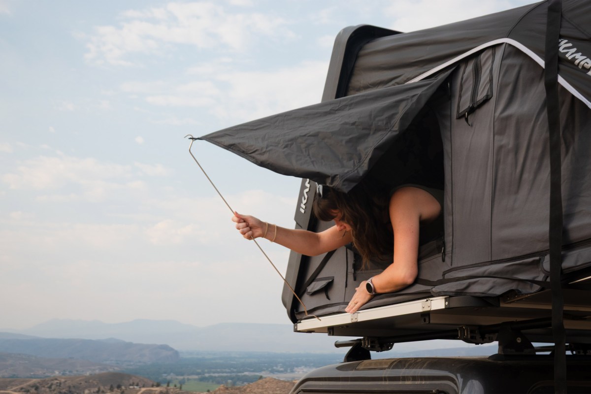 Woman installing a support rod on the iKamper camper window awning