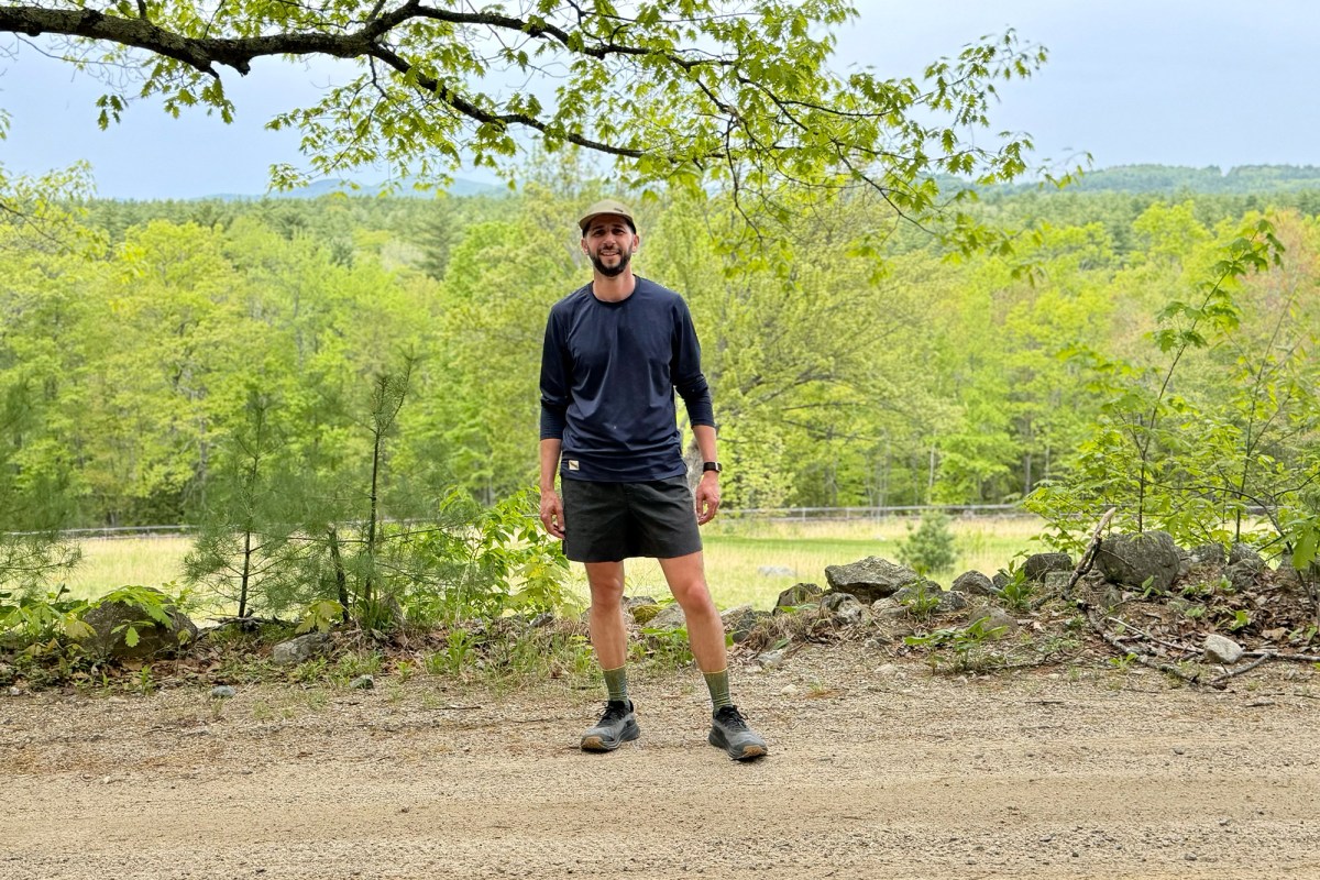Man wearing Trail Daemon shorts beside a green valley