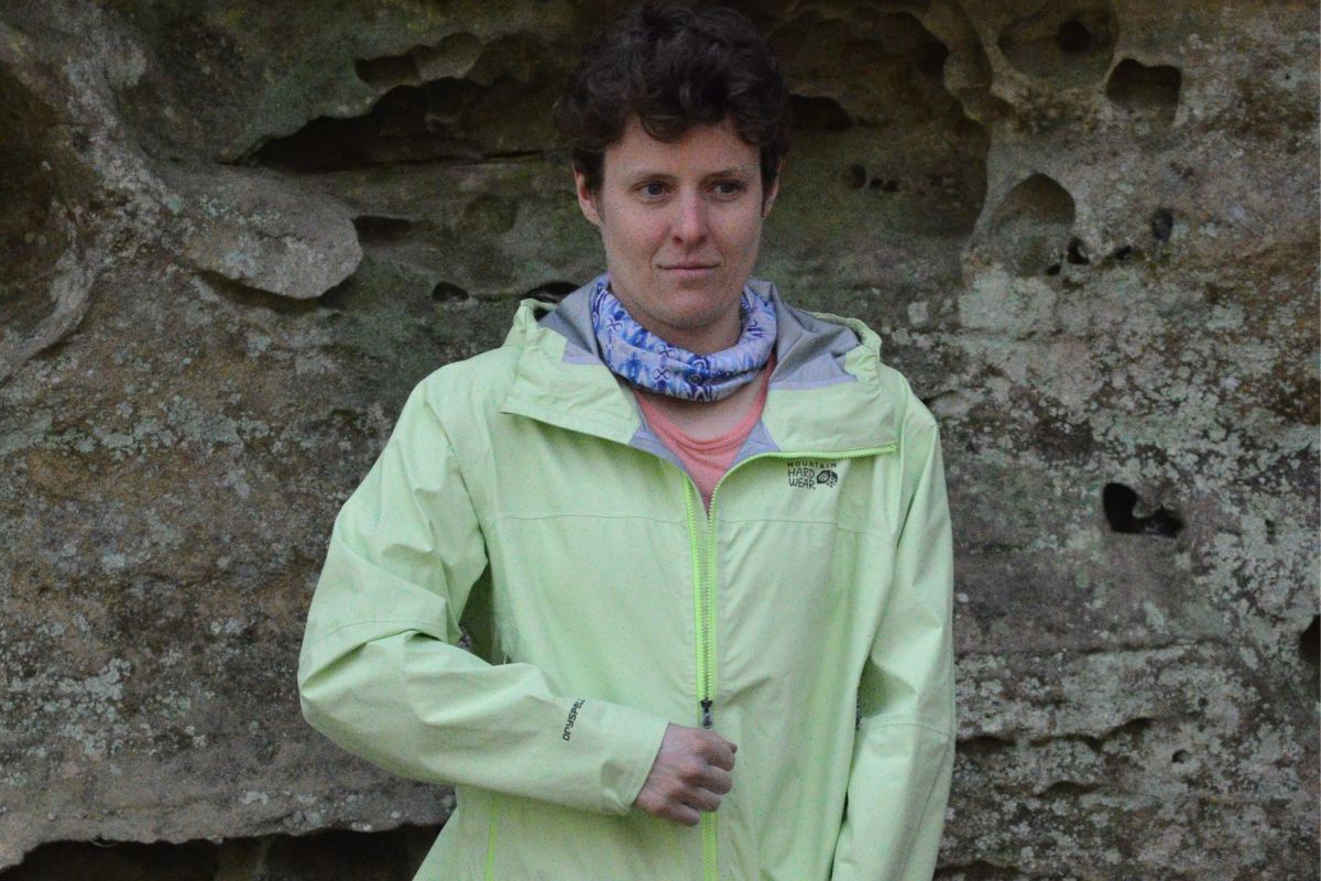 person zips up green rain jacket