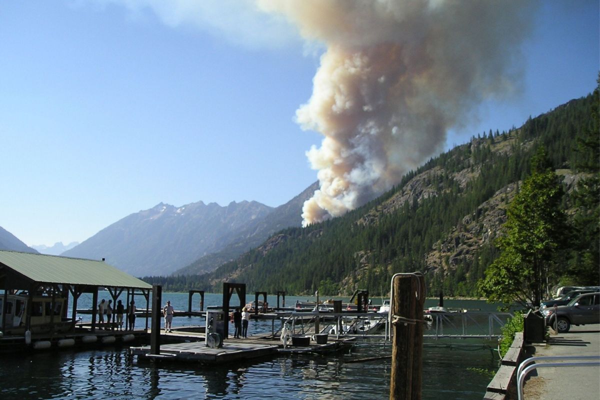 dock on a lake with fire in distance