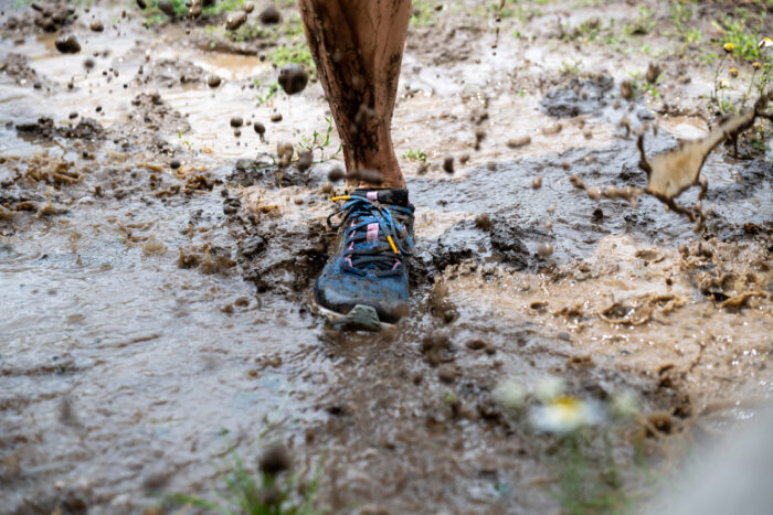 Close up of trail running shoes on muddy trail 