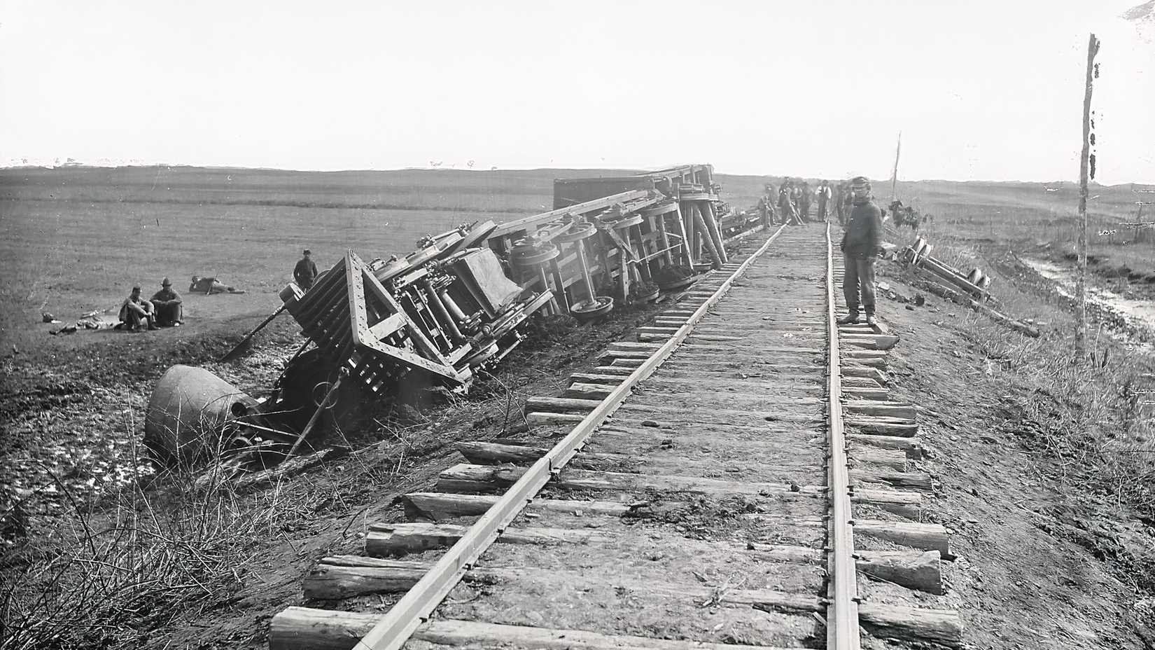 Men stand beside overturned railroad cars and scattered debris after the Union retreat from the Second Battle of Bull Run.