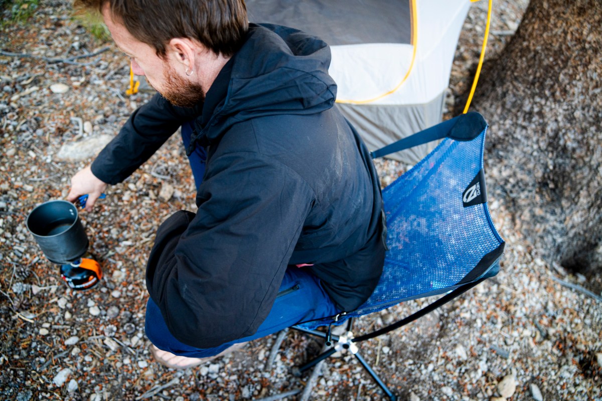 A man sits down into a NEMO backpacking chair