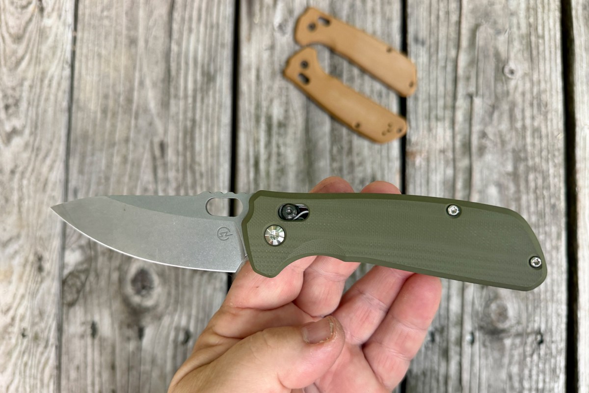 Green-handled Enduro knife held open above a weathered wooden surface