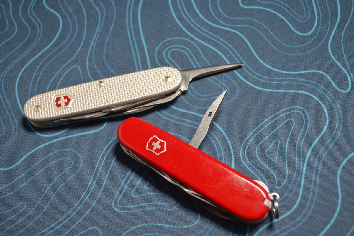 Red Victorinox Huntsman and silver Swiss Army knife with their awls open