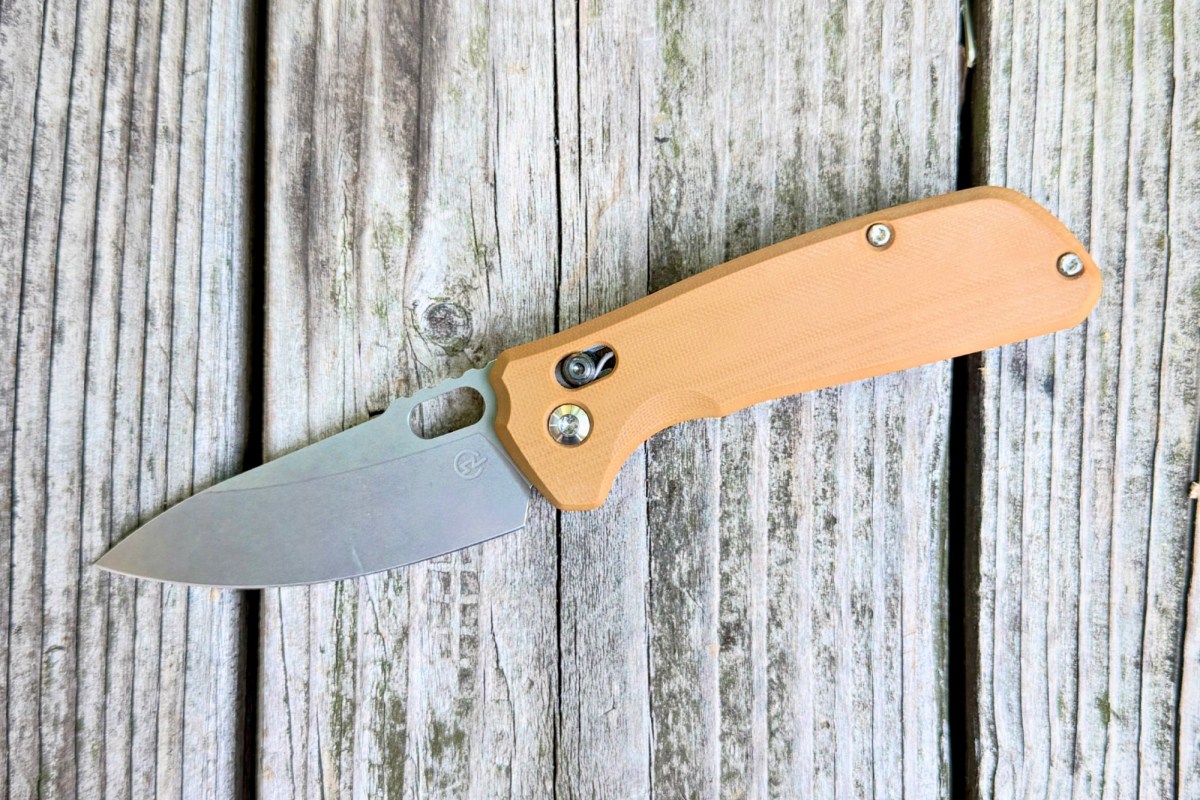 Schwarz Knives Enduro knife with tan handle resting open on weathered wood