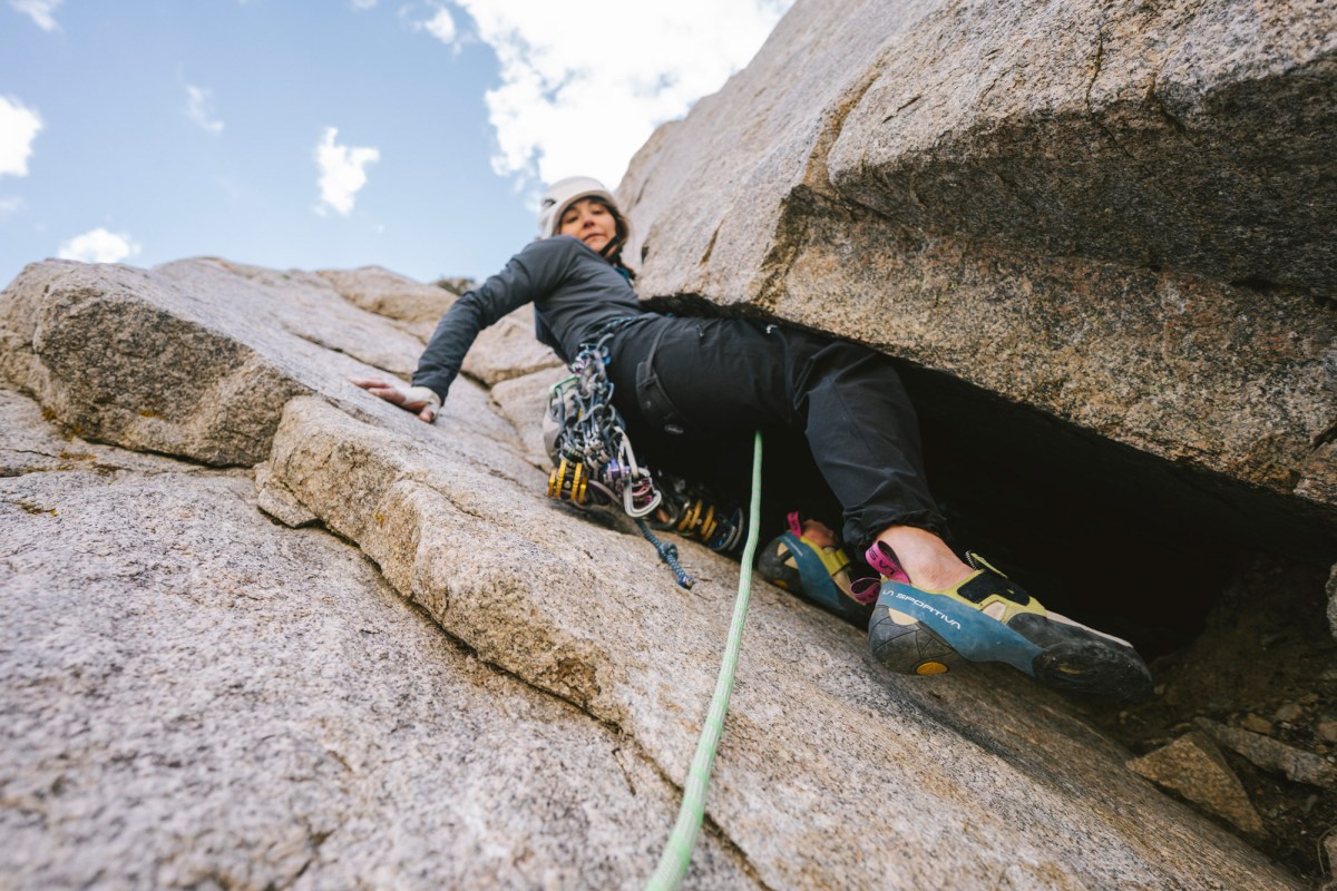 Climber wearing The North Face pants while moving through a wide granite crack