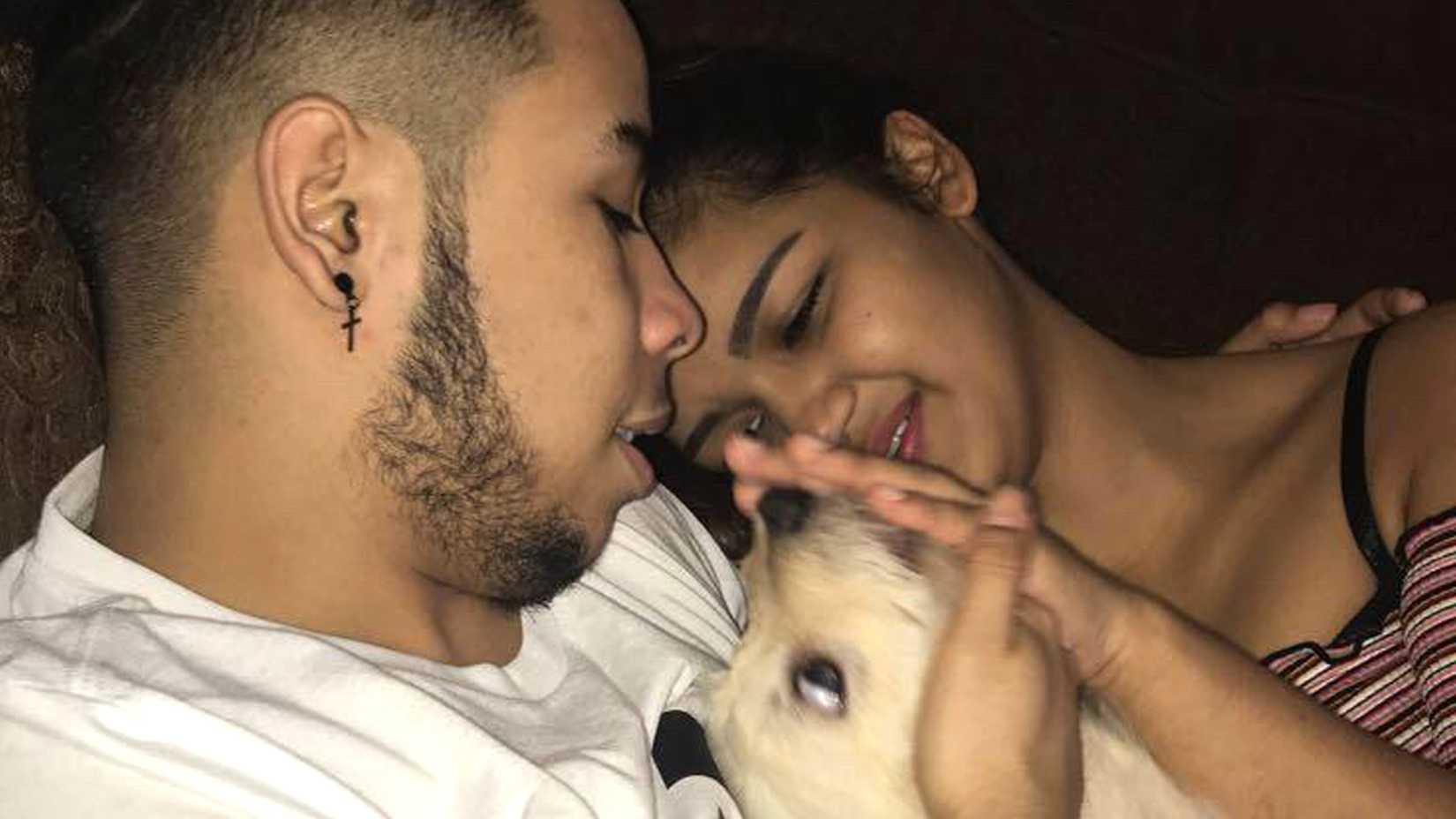 Hedár Leonel Turcios Juárez and Cristy Maryori Villafranca Trejo smile at each other while petting a tan dog.