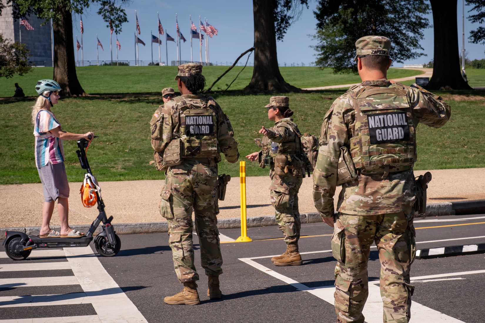 National Guard troops stop a young woman on a rental scooter