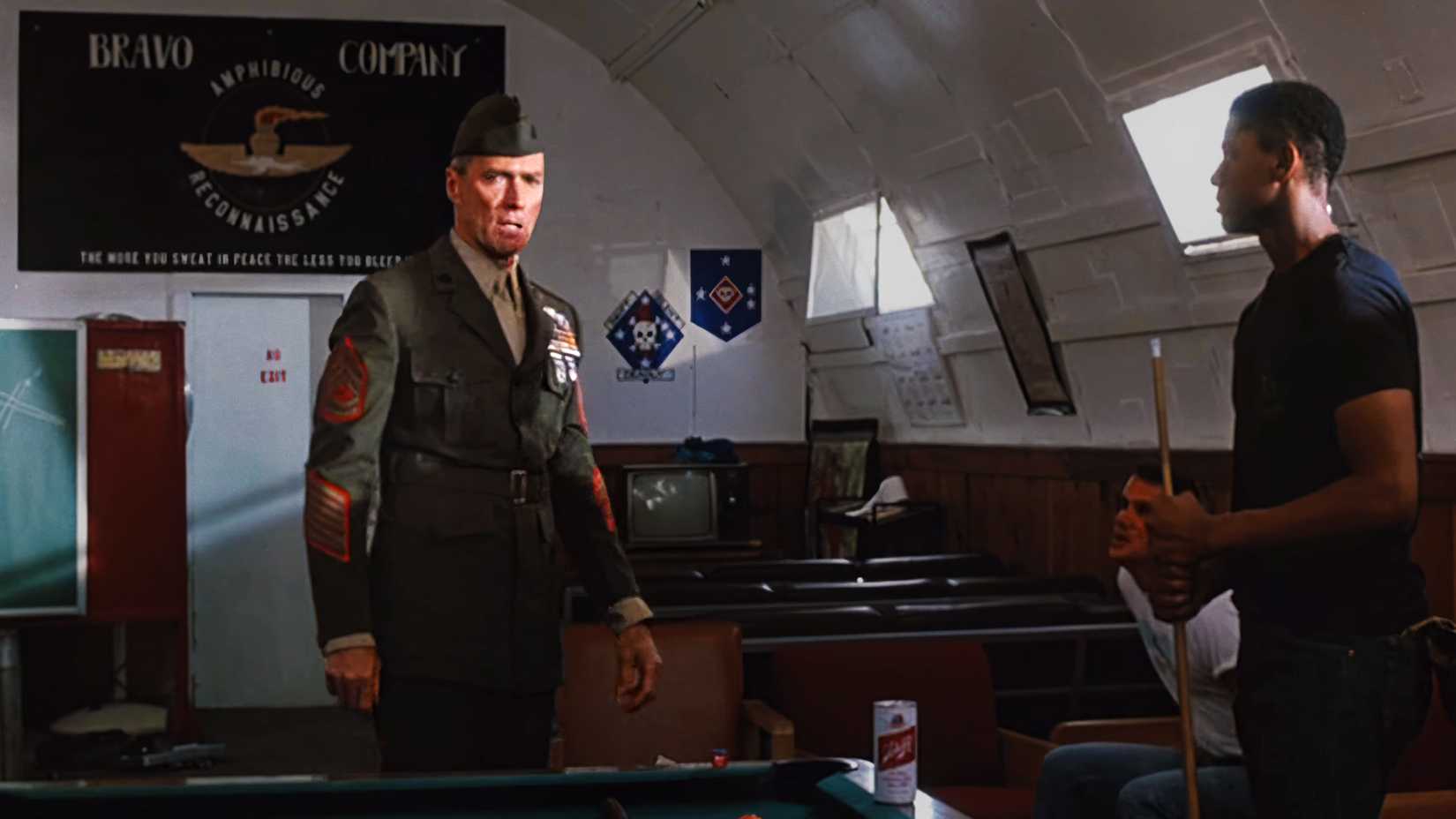 Clint Eastwood as Marine Gunnery Sgt. Tom Highway standing in uniform near a pool table in the 1986 film Heartbreak Ridge.