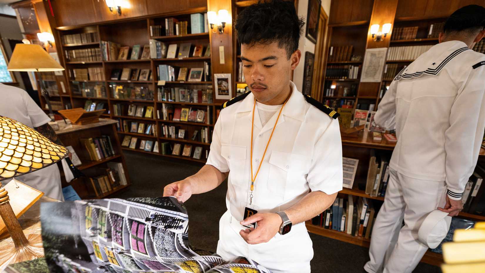 Navy Ensign Gabe Tayco flips through a large book inside the Rare Book Room at Powell’s Books in Portland.