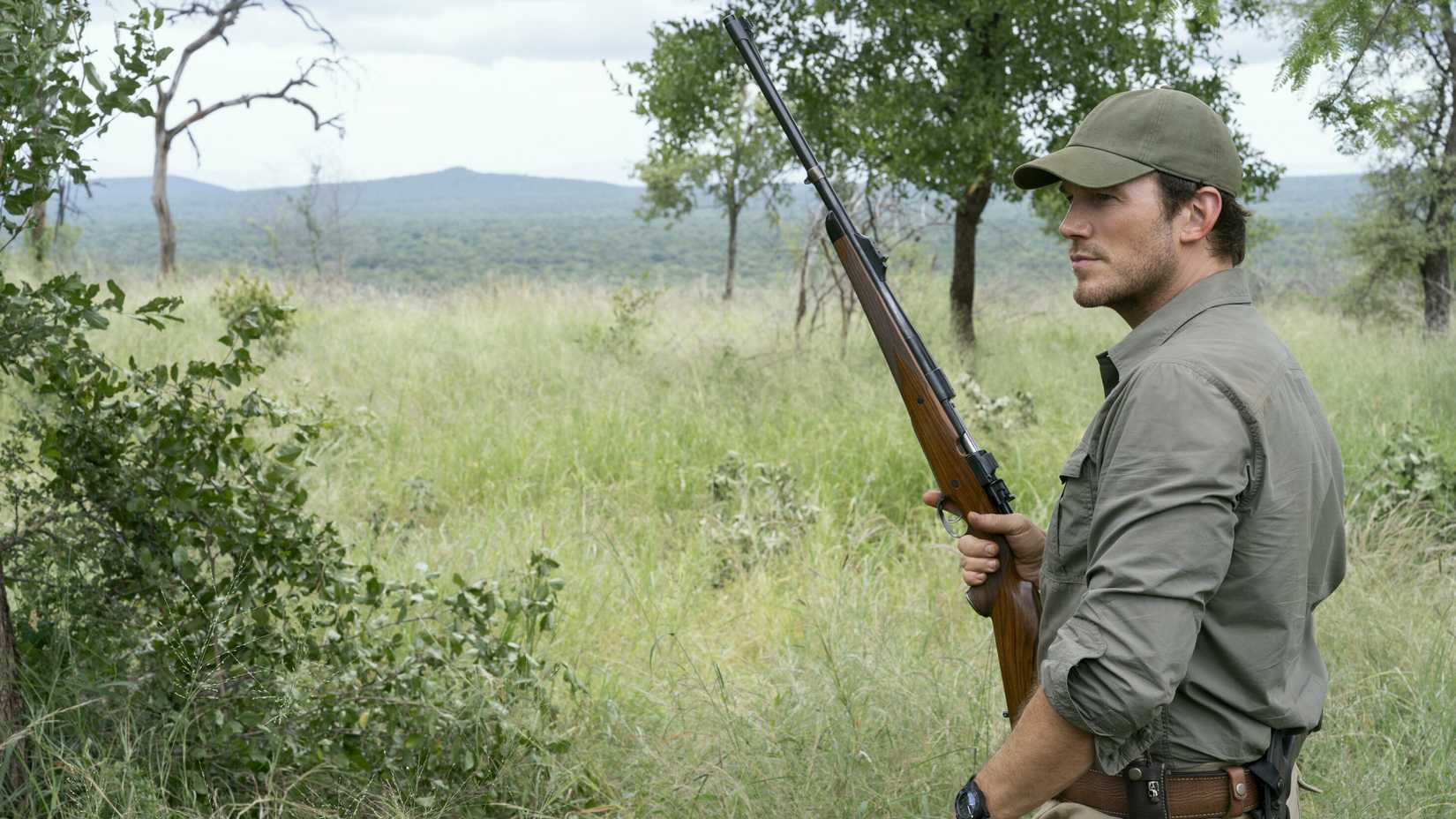 Chris Pratt as James Reece carrying a rifle through a grassy, wooded area in a scene from The Terminal List Season 2.